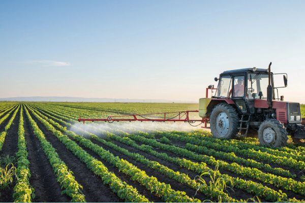 A tractor spraying pesticides on a green field.